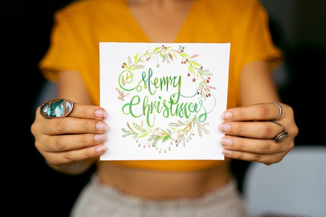 A woman holding a card with "Merry Christmas" written on it.